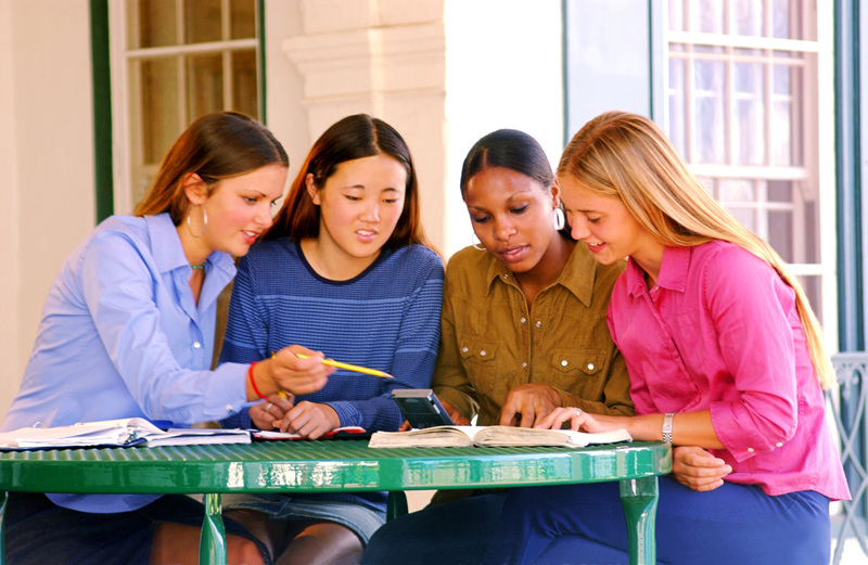 عکس، چهار دختر نوجوان در حال مطالعه پشت میز در فضای باز، رنگی