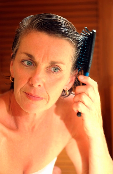 عکس، نمای نزدیک از زنی که موهایش را بعد از حمام شانه می کند، رنگی