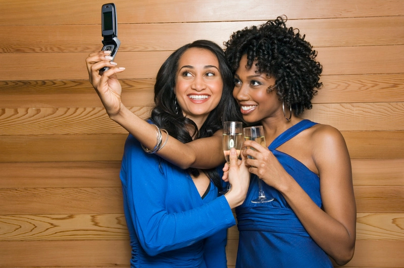 زنان با شامپاین در حال عکس گرفتن با تلفن همراه از خود