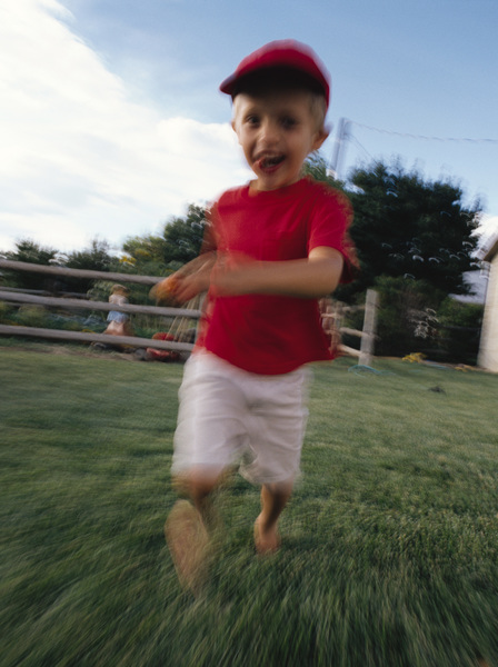 عکس انتزاعی تار از یک پسر جوان قفقازی که با لباس قرمز بیسبال در حیاط خلوت خود می دود