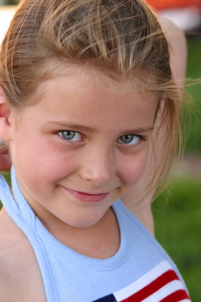 عکس سبک زندگی یک دختر کوچک قفقازی با تاپ آبی رنگ در حالی که لبخند می‌زند