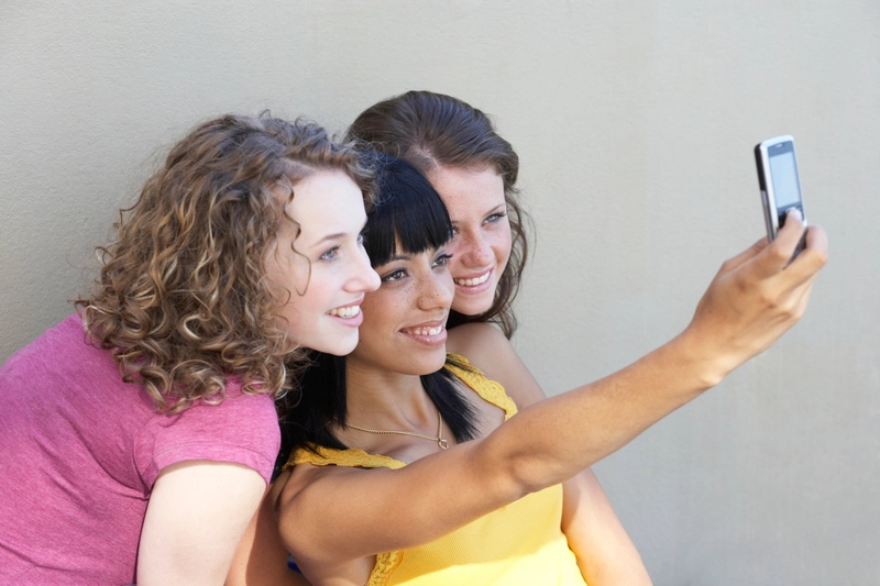 سه دختر با تلفن همراه عکس می گیرند