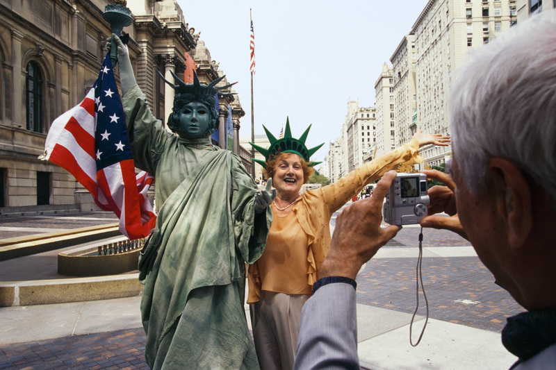 مردی در حال عکس گرفتن از زن با ماکت مجسمه آزادی