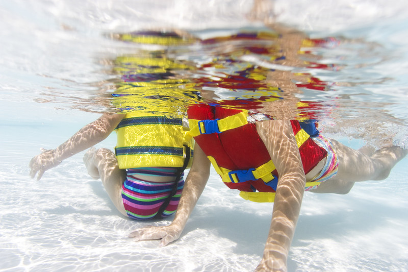عکس زیر آب از دو دختر نوپا در حالی که شنا کردن در استخر را یاد می گیرند