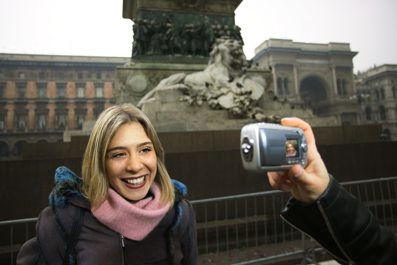 زنی عکس خود را با دوربین دیجیتالی که دوستش در میدان دومو، میلان، ایتالیا نگه داشته است، گرفته است.