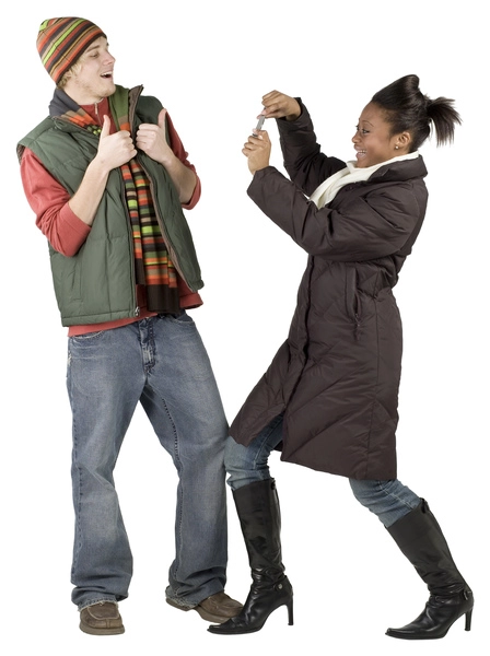 زن جوانی که لباس زمستانی پوشیده است و از مرد جوانی با تلفن همراه عکس می گیرد