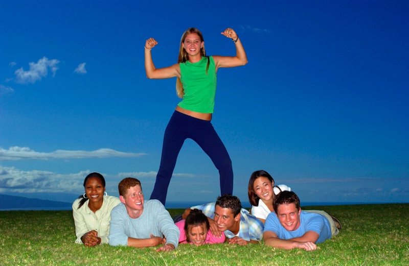 عکس گروهی از نوجوانان روی زمین دراز کشیده، یک دختر به پشت ایستاده، رنگی